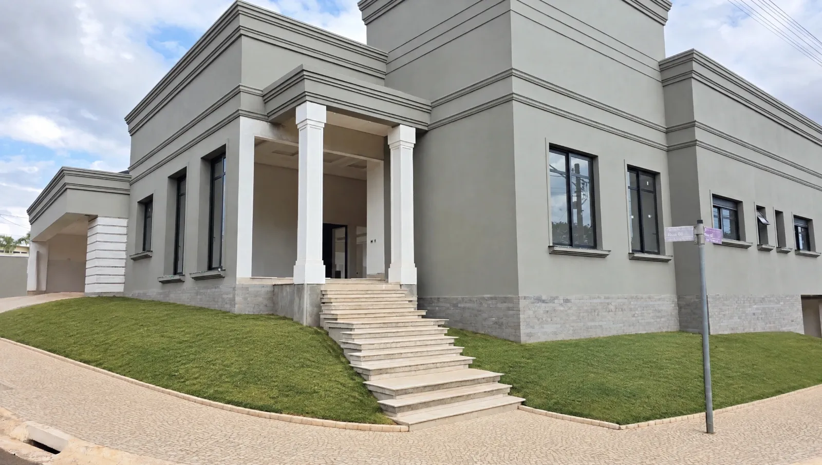 Photo of a neoclassical house front with a lawn and steps, before any garden