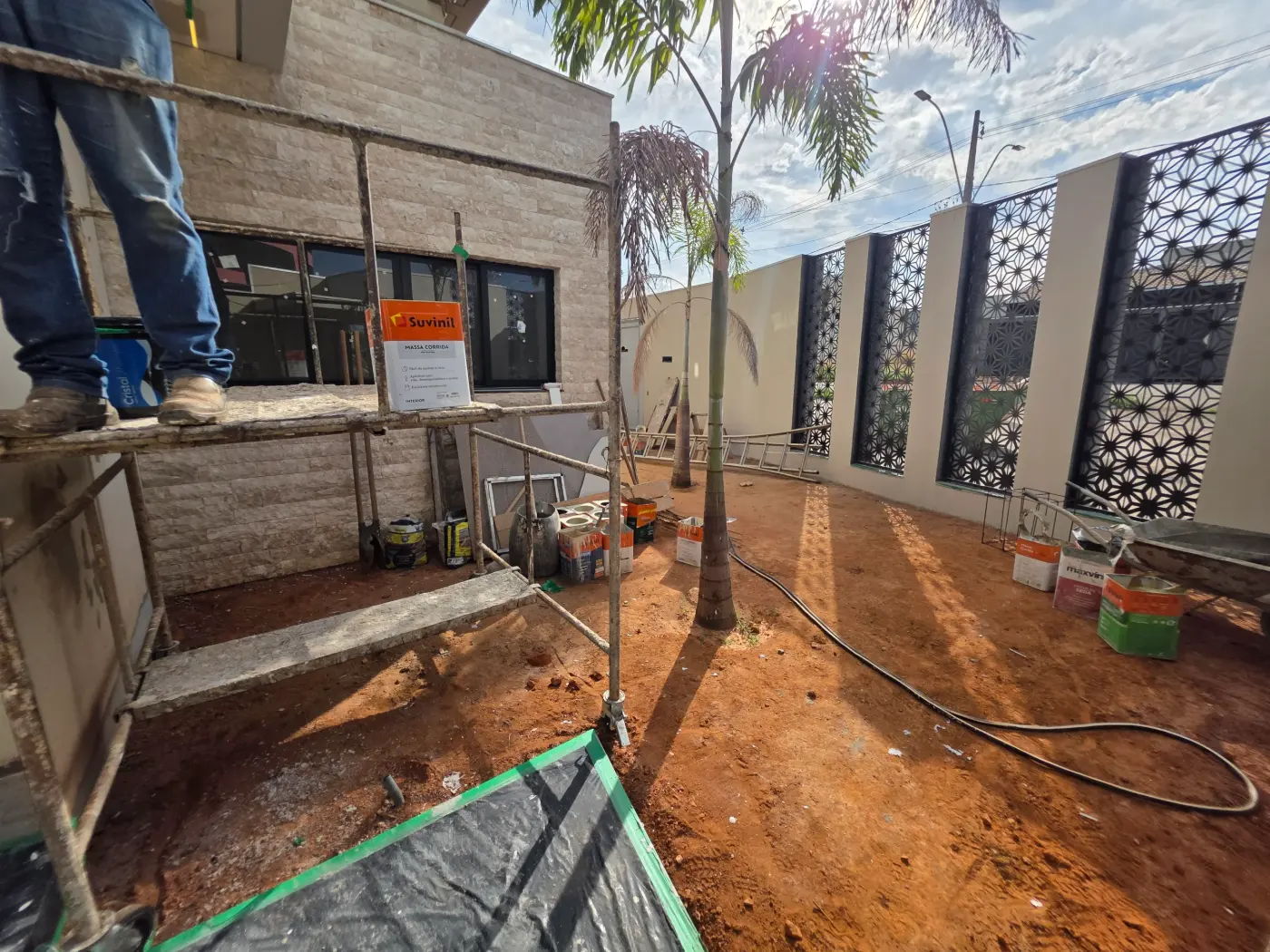 Before: a build site with scaffolding, a tarp, cans and a hose